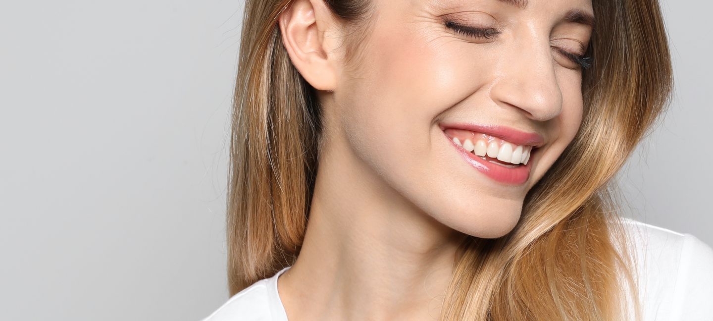 Uśmiechnięta dziewczyna, pokazująca naturalne zęby - stomatologia.